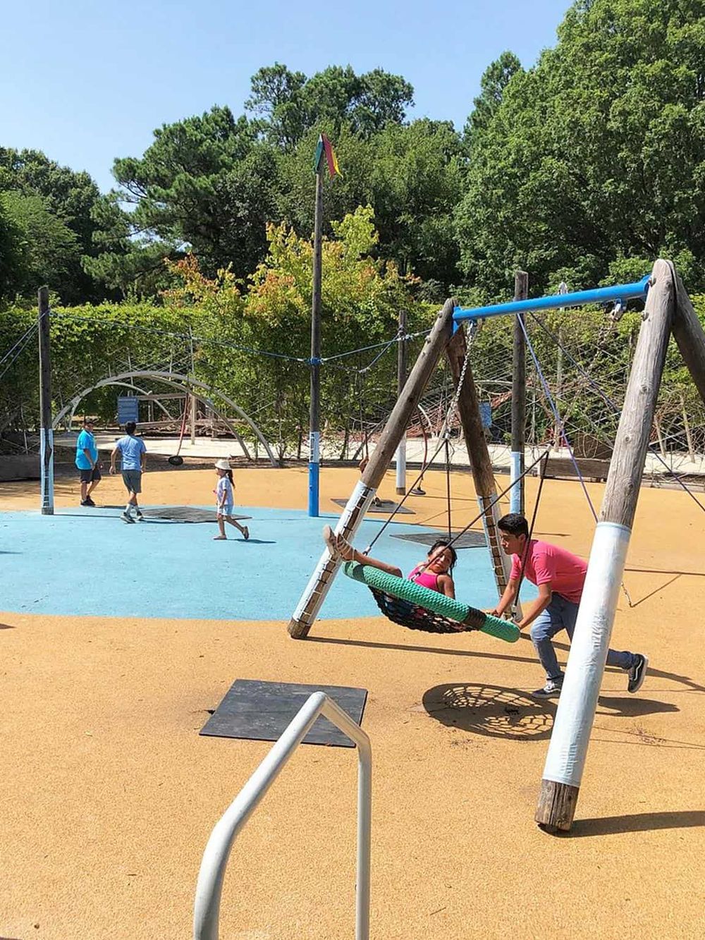 Kids swinging on a modern park swing set at Quest For Directions playground.