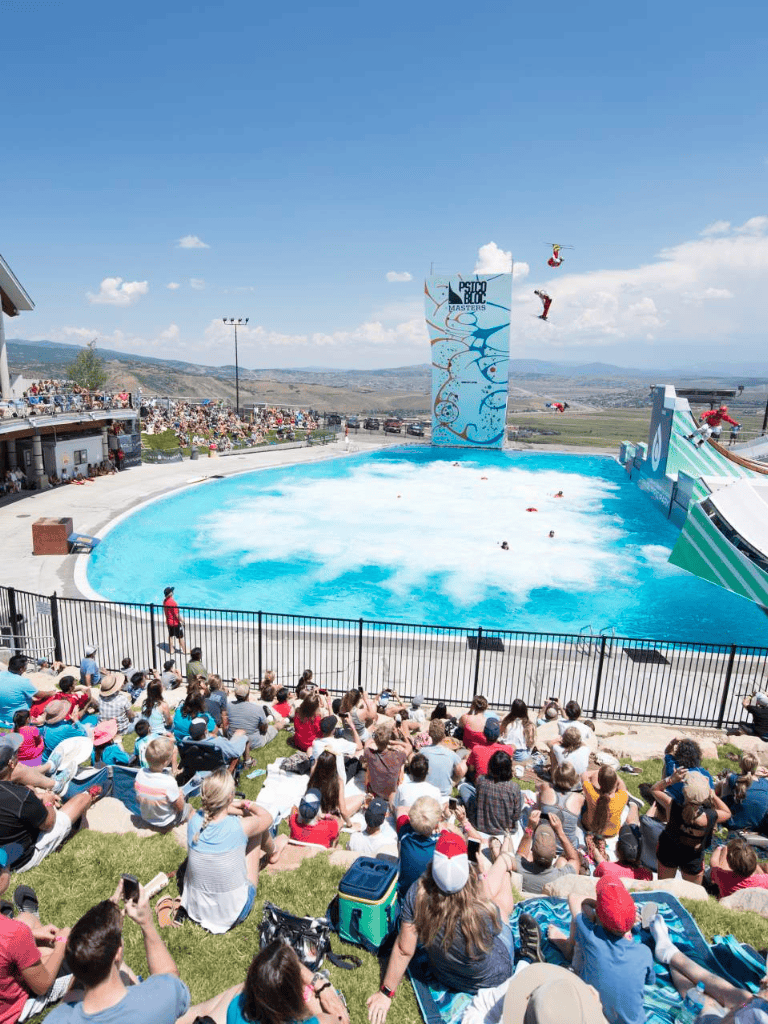 Dolphin show at Quest for Directions water park with audience watching thrill rides and wave pools.