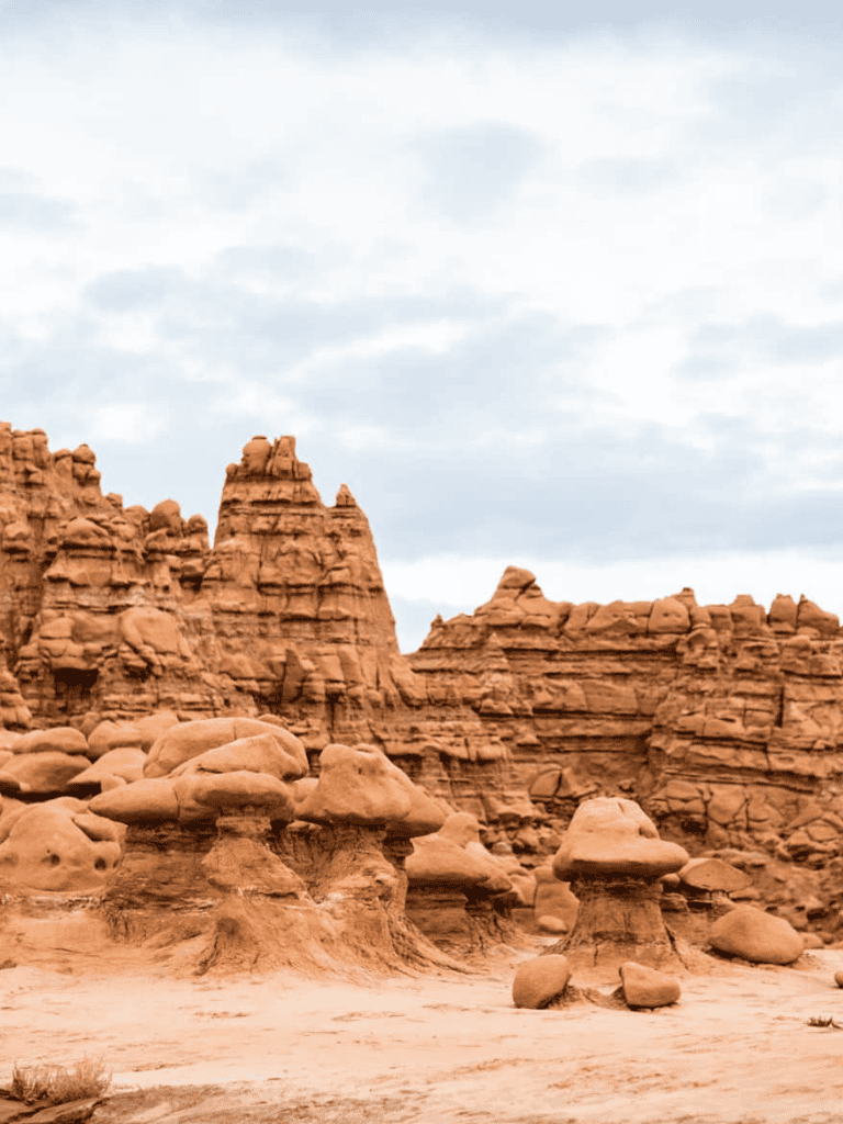 Colorful hoodoos in a desert landscape with red rock formations and cloudy sky, perfect for Adventure and Travel keywords.