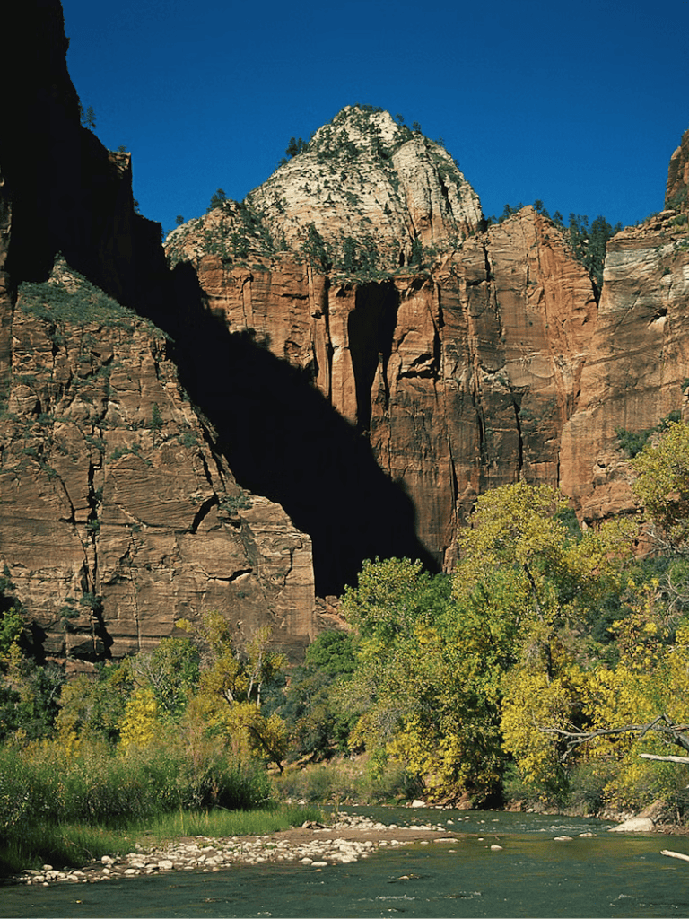 Vivid Zion National Park cliffs and canyon landscape in Utah with clear river in foreground.