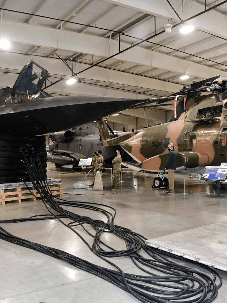 Fighter jets displayed in a museum with cables and informational plaques.