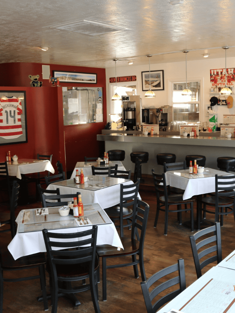 Cozy sports-themed restaurant interior with white tablecloths, black chairs, and sports memorabilia.