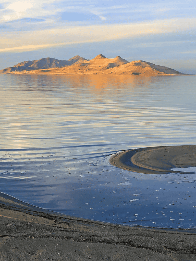 Serene lake with mountains in the background at sunset, perfect for peaceful nature exploration.