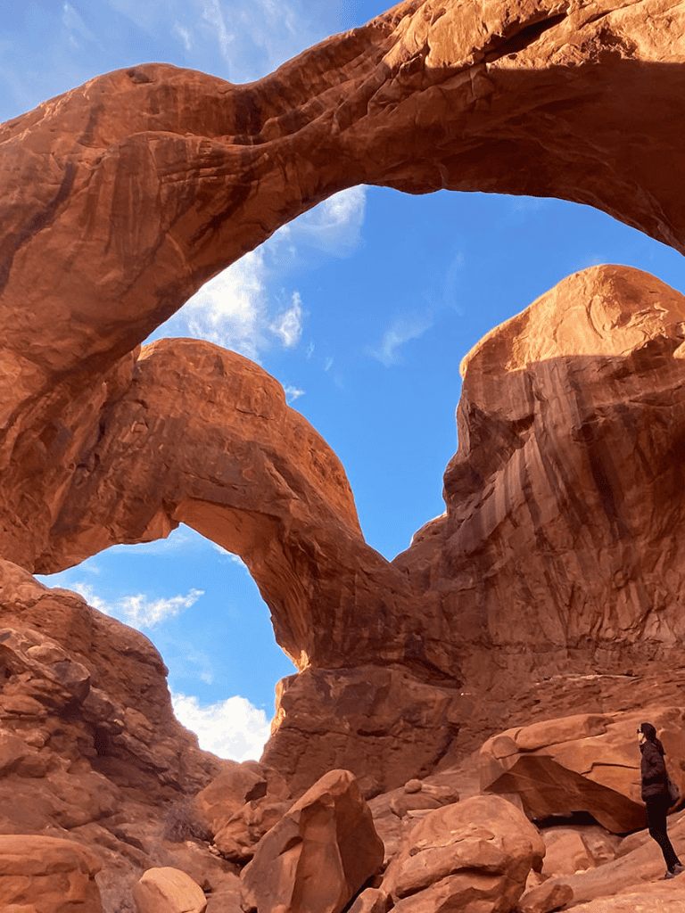 Vivid red rock formations with natural arches in a desert landscape under a blue sky.