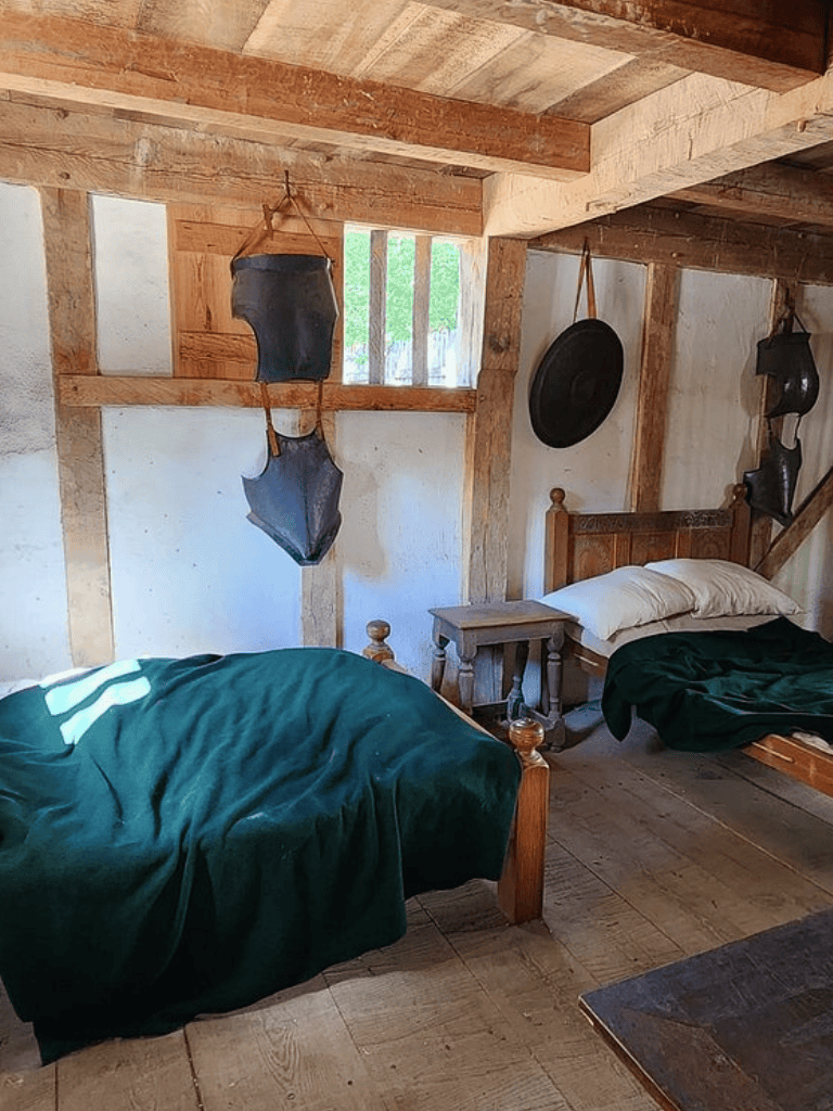 Cozy rustic bedroom with wooden beams, vintage bed frames, and antique decor elements.