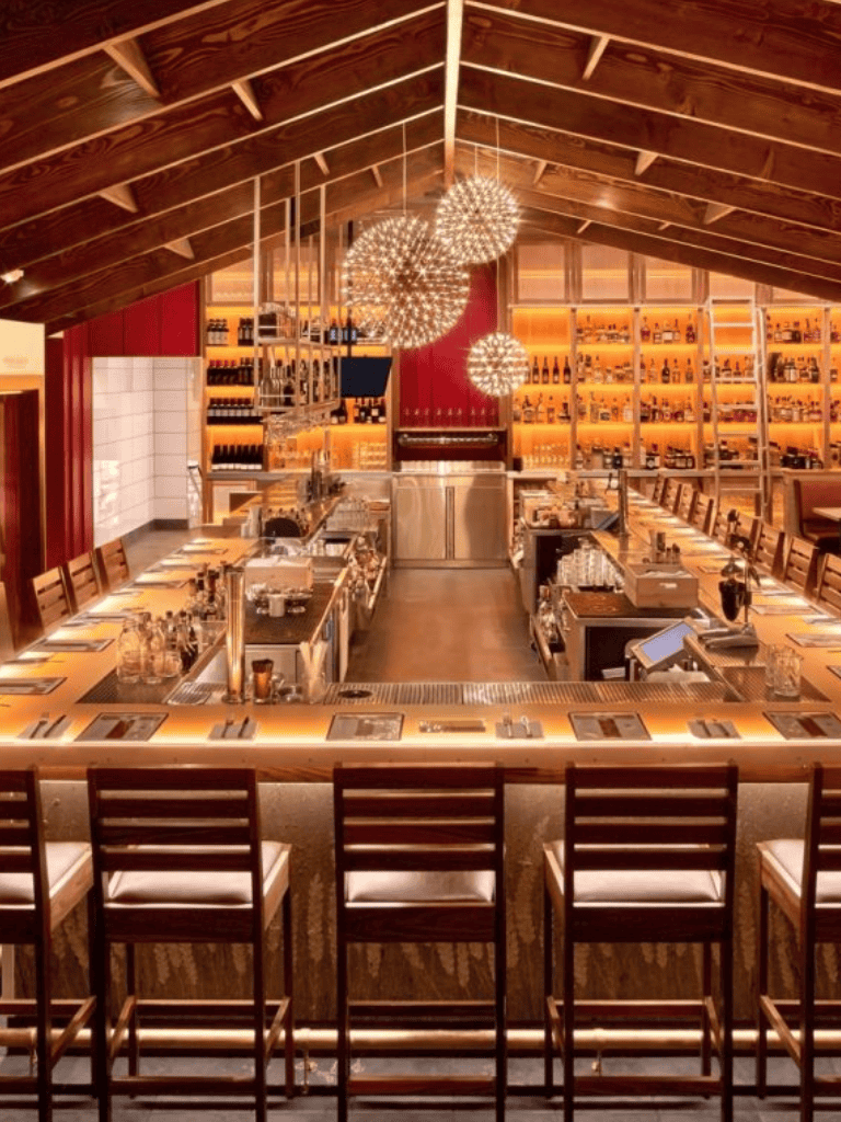 Elegant restaurant bar with warm lighting, modern decor, and cozy seating for dining and cocktails.