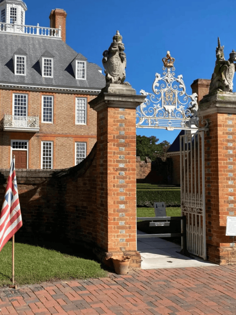 Historic brick estate gate with ornate ironwork and classical sculptures.
