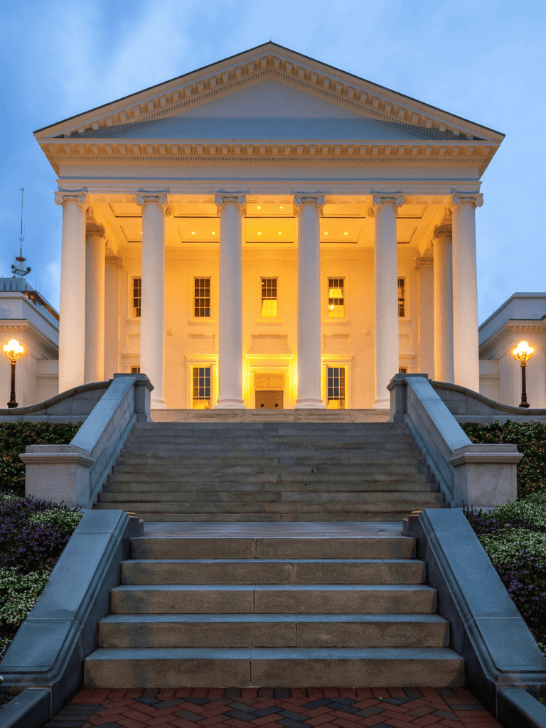 Elegant government building with neoclassical columns and grand staircase at dusk.
