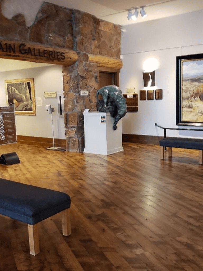 Quiet museum interior with art sculptures, paintings, and wooden flooring, part of QuestForDirections exhibit.