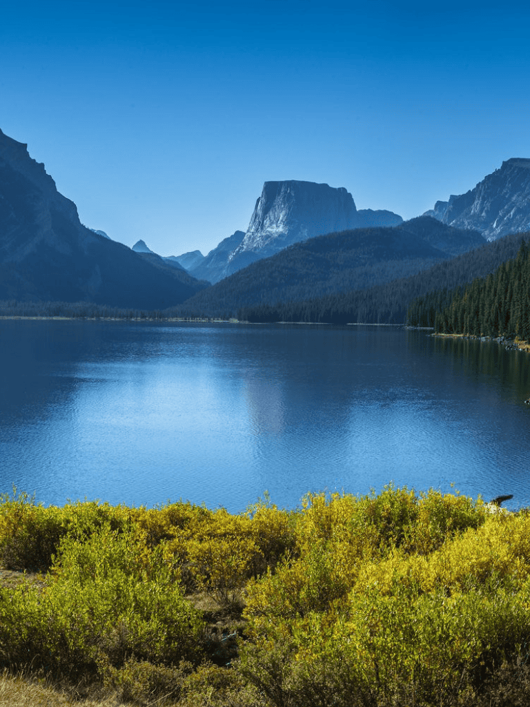 Serene mountain lake surrounded by lush green landscape and towering peaks, perfect for outdoor adventures.