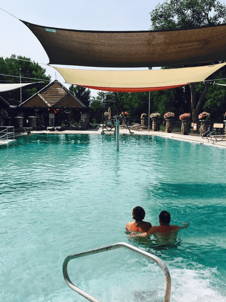 Sunny poolside with shade sails at QuestForDirections outdoor swimming pool.