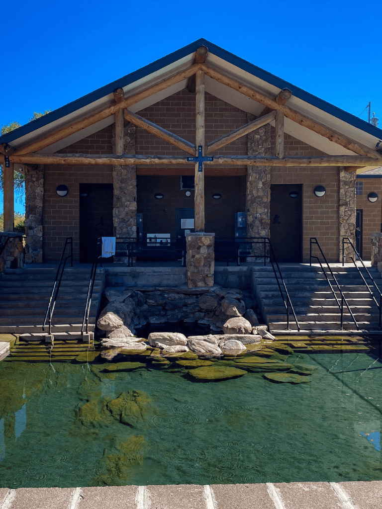 Rustic lodge with stone accents and pond, perfect for outdoor adventures and nature retreats.