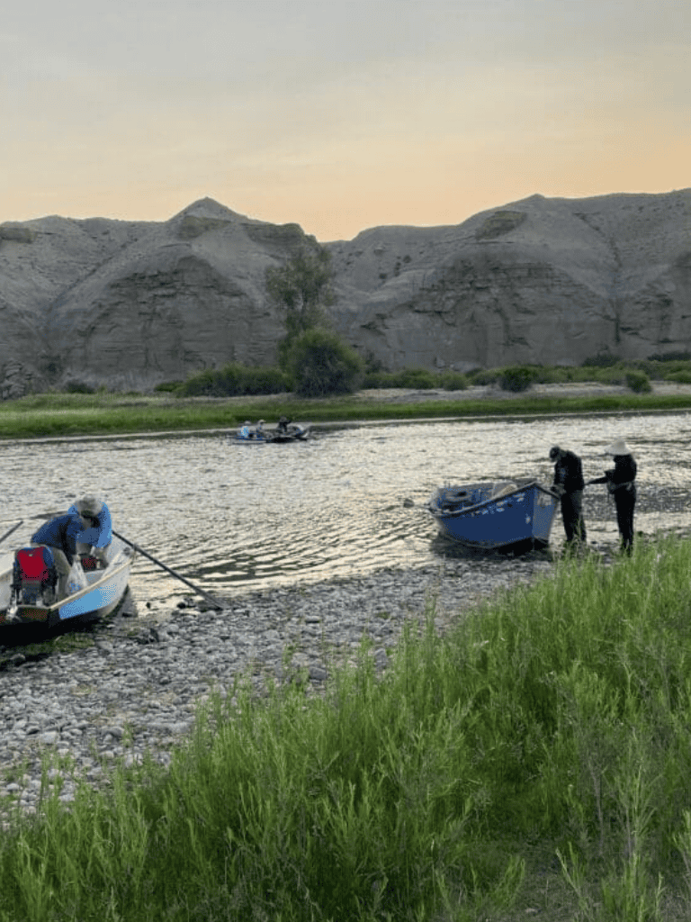 Boats on river with rocky canyon background during sunset.