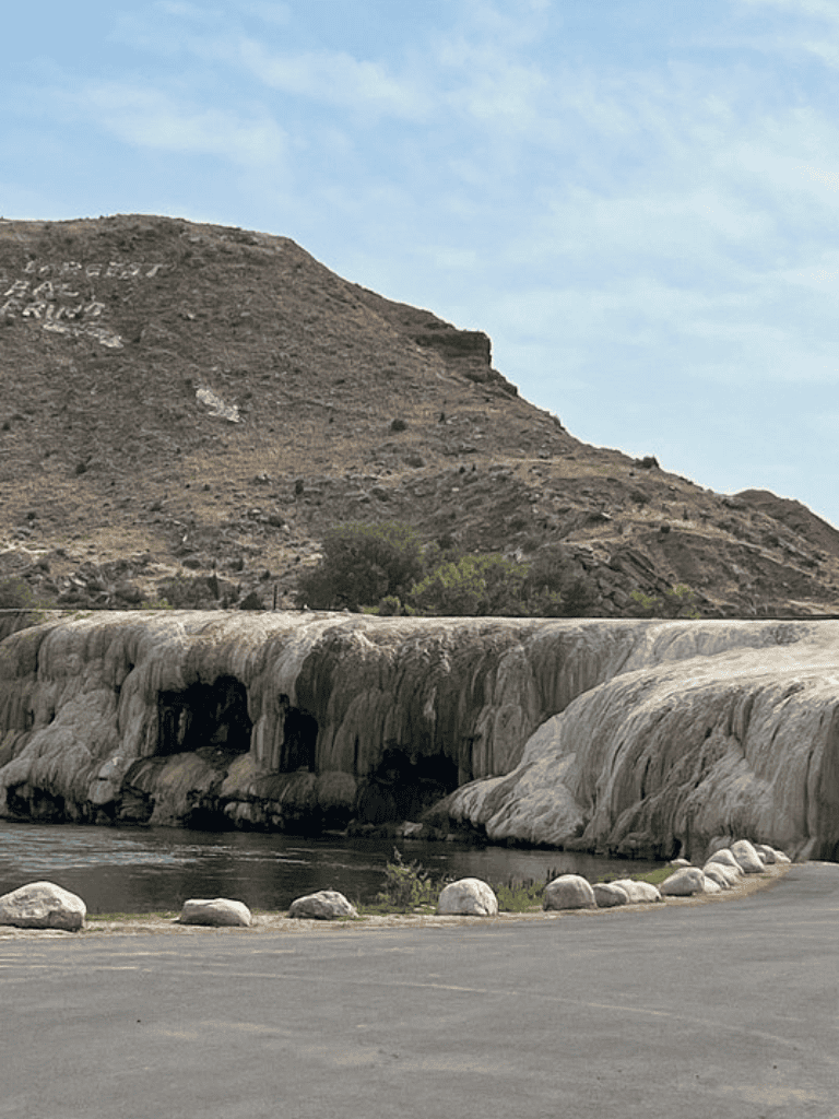 Colorful mineral deposits along a waterway with a desert mountain backdrop in California.