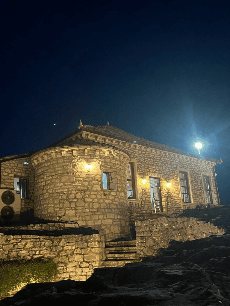 Cozy stone house illuminated at night with steps leading up to the entrance.