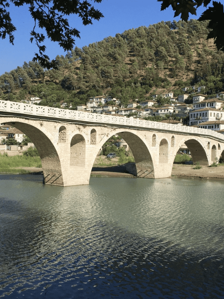 Stone arch bridge over river in a scenic mountain town.