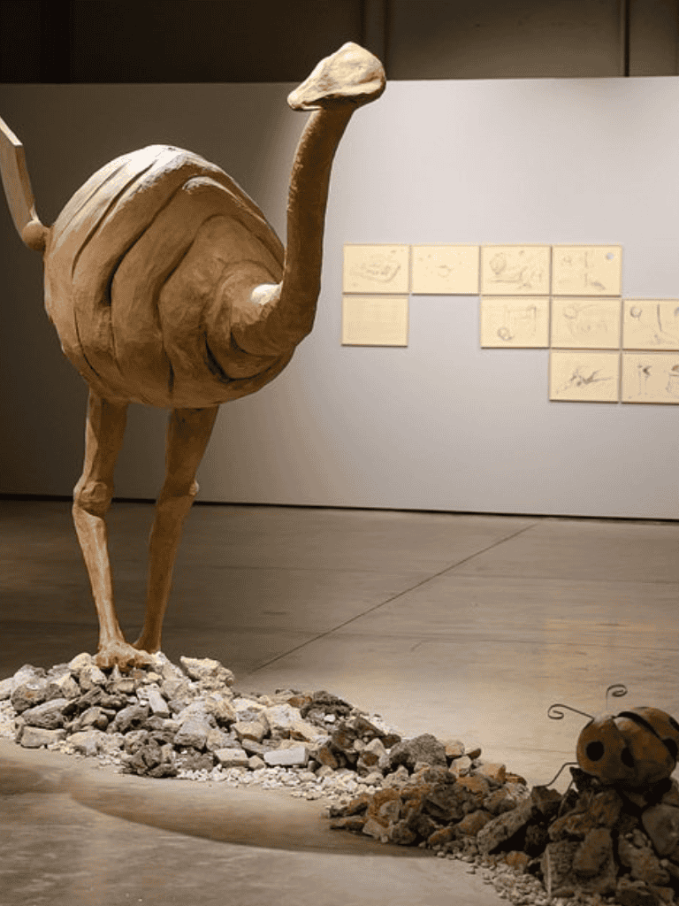 Large wooden camel sculpture with detailed construction, displayed in a museum setting.