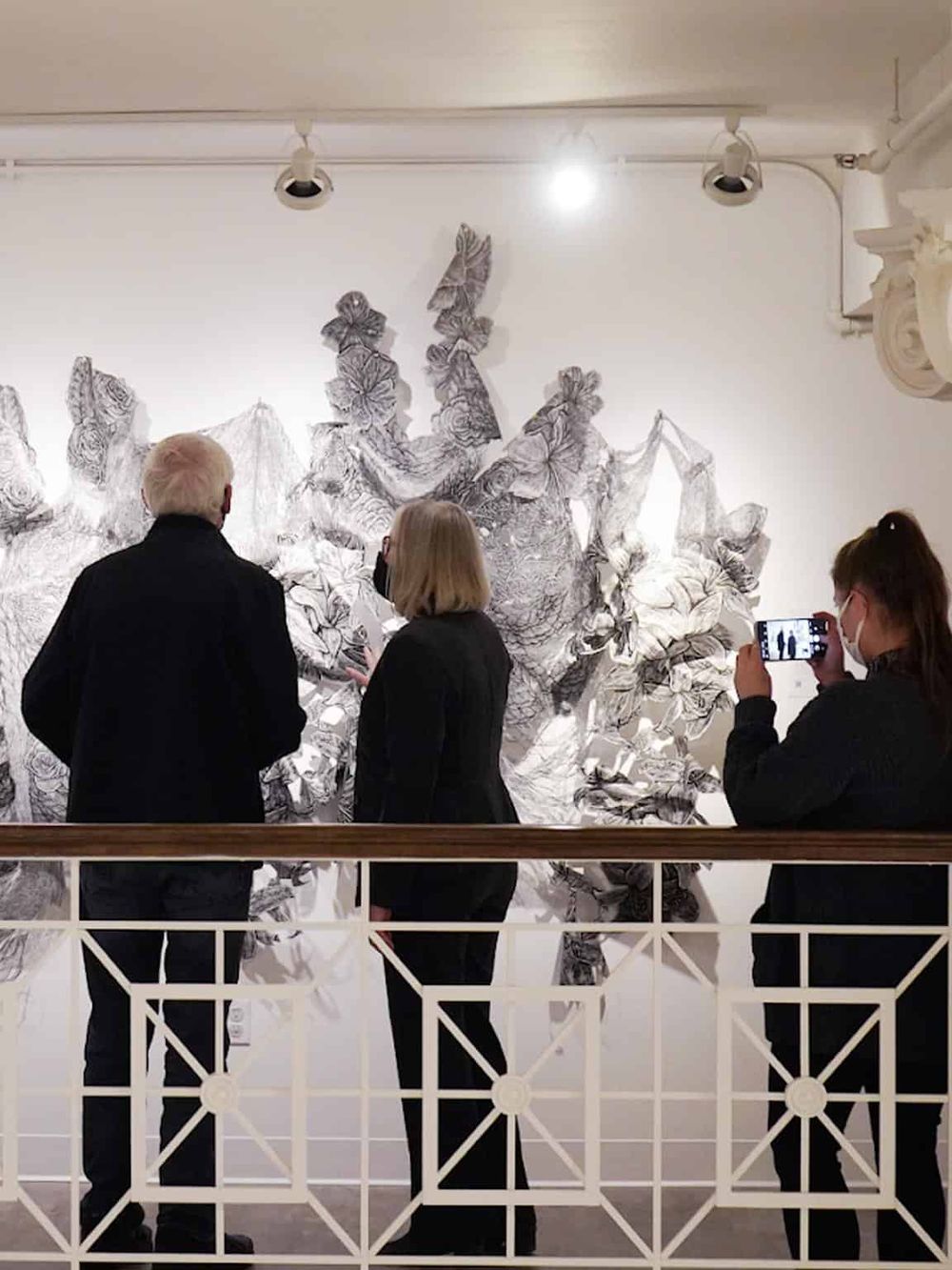 Vivid black and white artwork at QuestForDirections art exhibit with visitors observing and photographing.