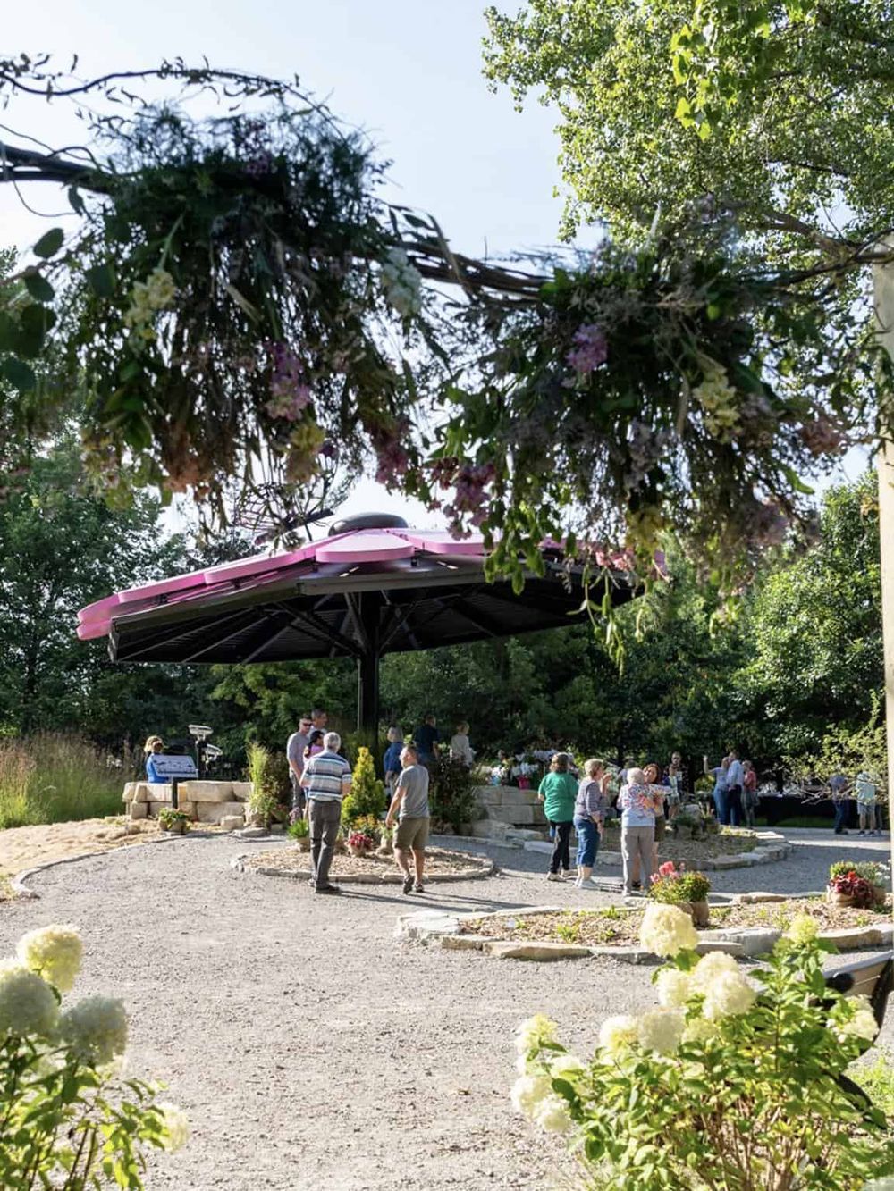 Colorful outdoor community gathering with gazebo and blooming flowers, perfect for events and outdoor activities.