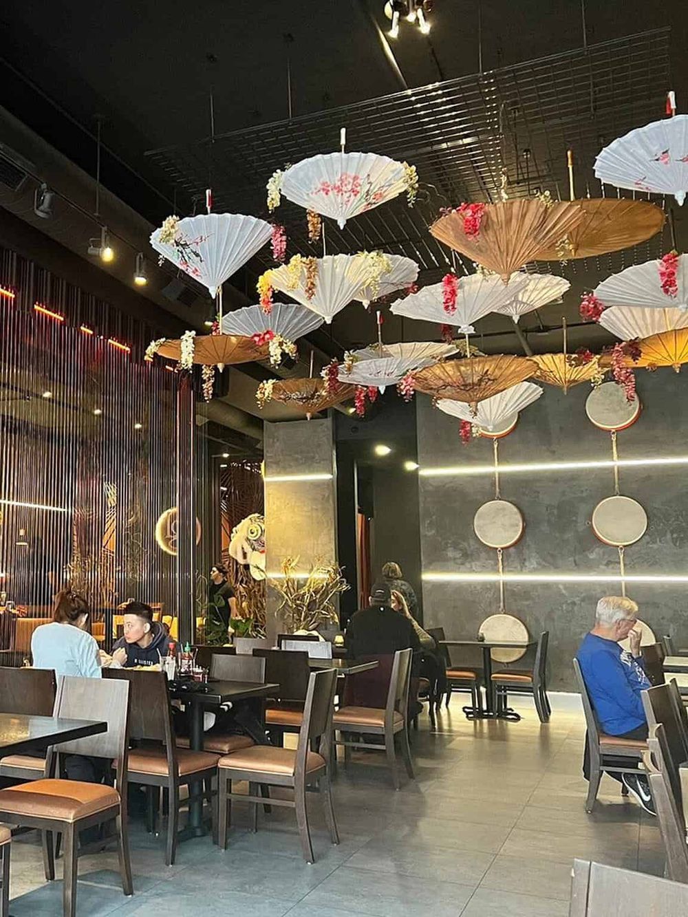Colorful paper umbrellas and floral decorations in a modern restaurant interior.