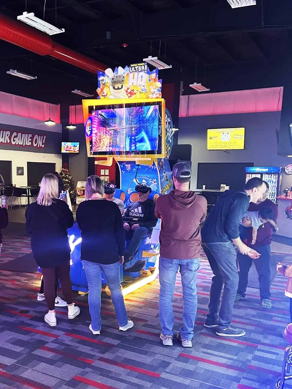Bright arcade game with players wearing VR headsets, lively entertainment environment, colorful lighting, and gaming area.