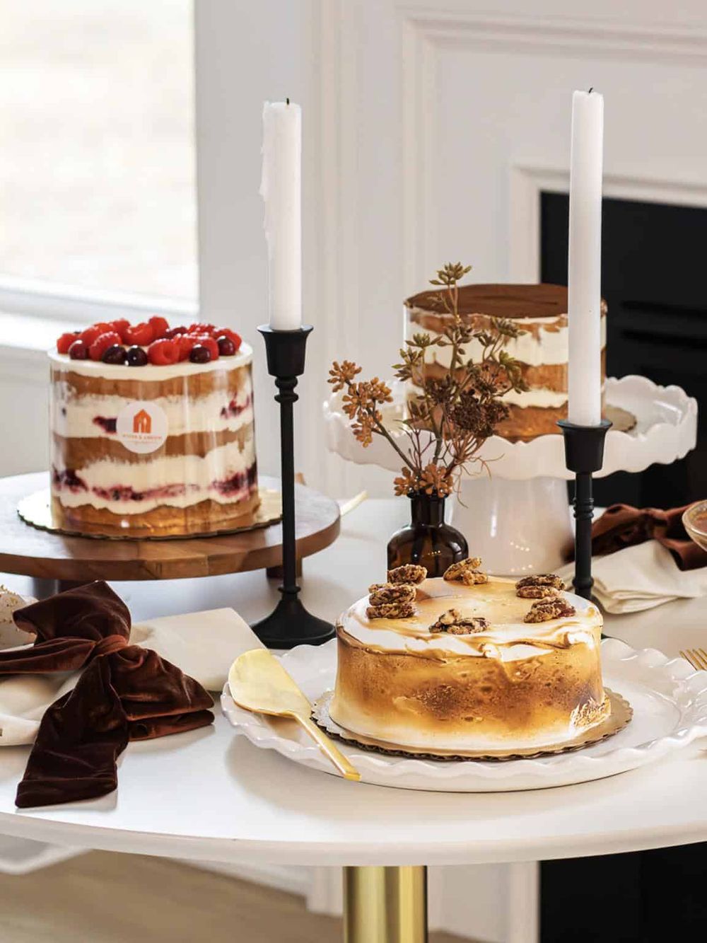 Elegant dessert table with layered cakes and candles for special celebration.