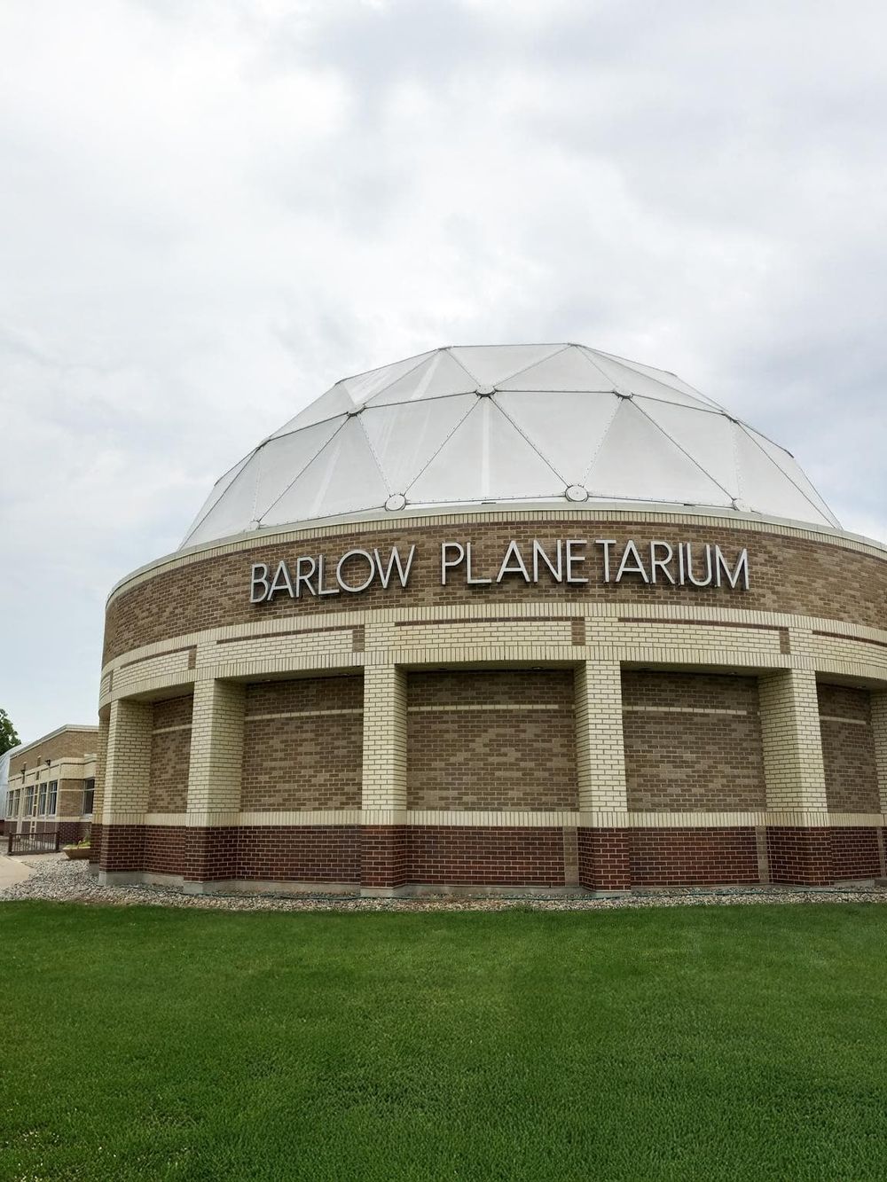 Brightly lit Barlow Planetarium with brick exterior and geodesic dome, part of QuestForDirections.