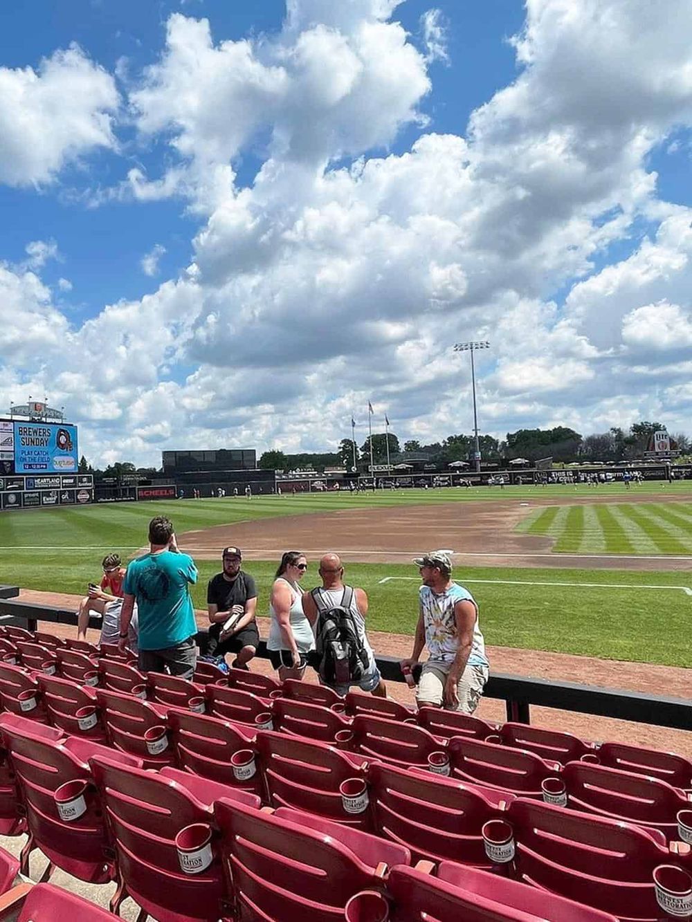 Bright baseball stadium with fans, cloudy sky, and lush field, showcasing sports, outdoor entertainment, and event planning services.