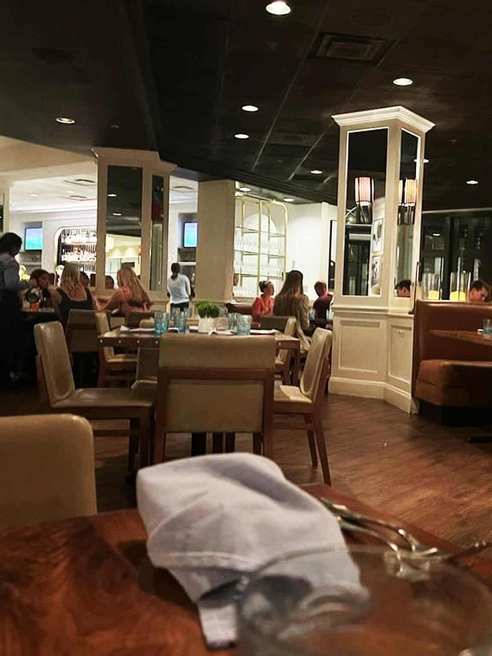 Cozy restaurant interior with elegant decor, busy diners, and attentive wait staff.