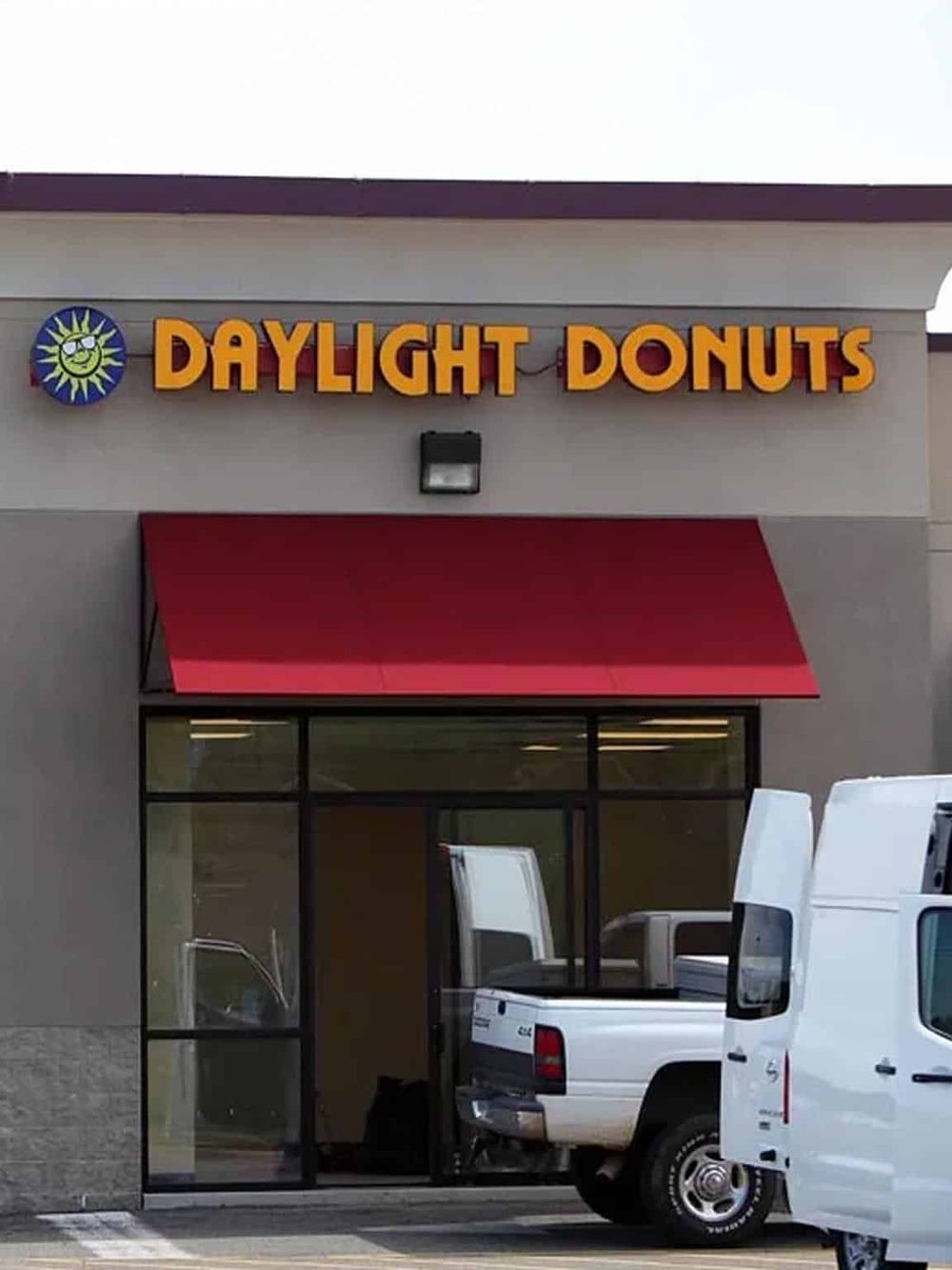 Bright Daylight Donuts storefront with red awning and parking lot.