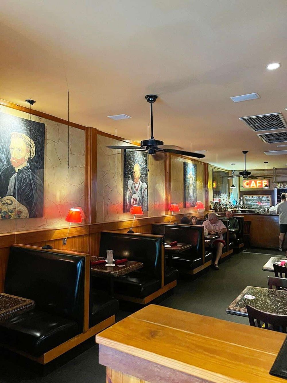 Cozy restaurant interior with artwork, red lamps, and seating for dining and casual meals.