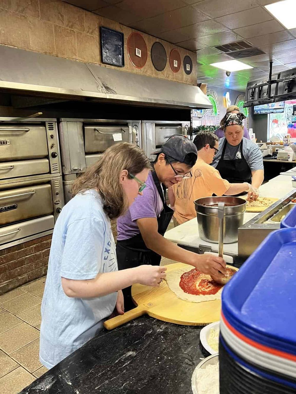 Freshly making pizza in a busy kitchen with diverse staff at QuestForDirections.