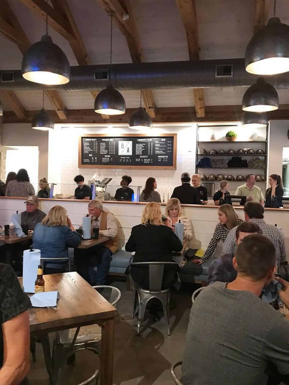 Cozy modern restaurant interior with customers enjoying meals and a visible menu board, perfect for dining and food delivery services.