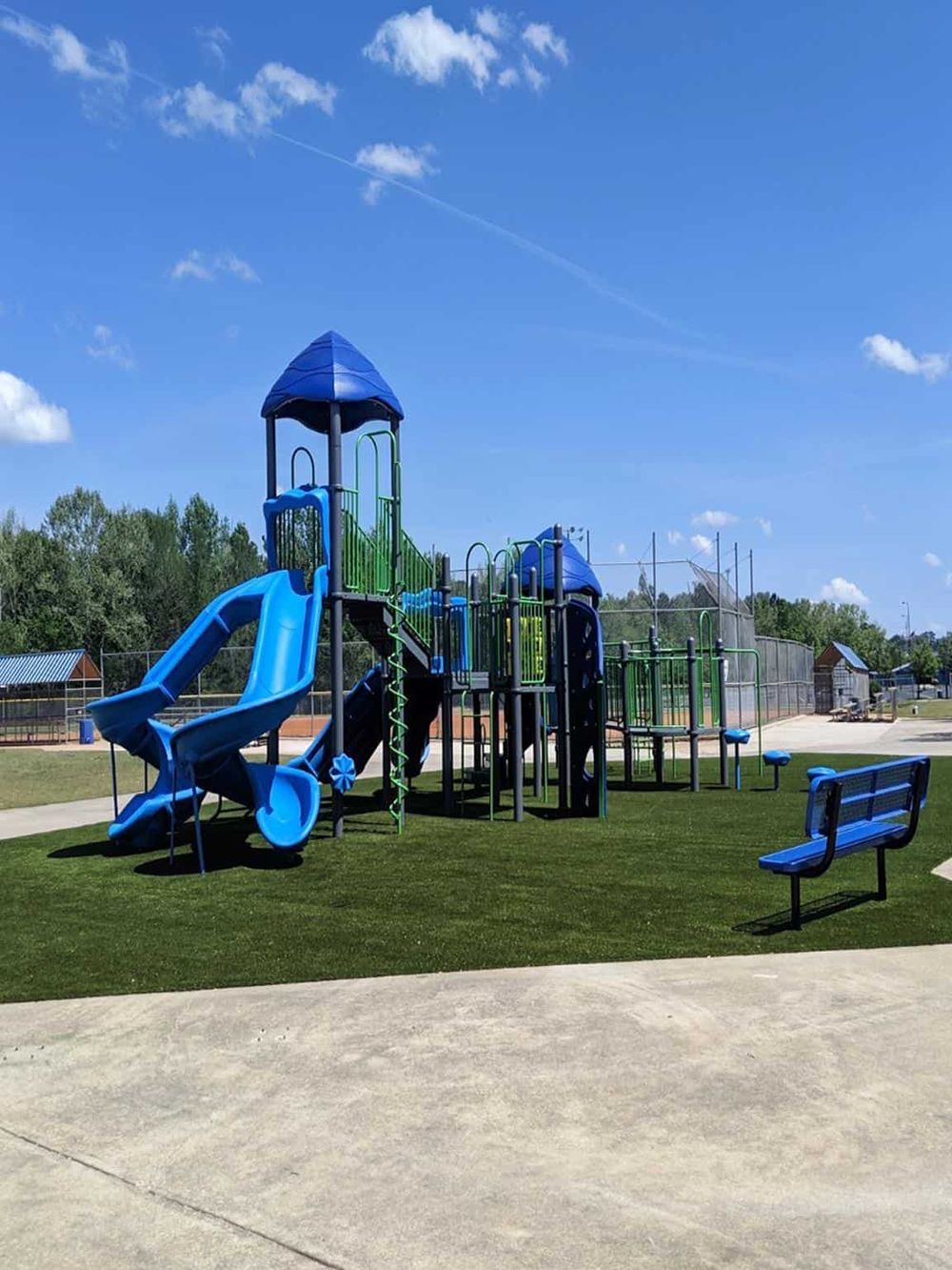 Bright blue playground equipment at outdoor park with slides and climbing structures.