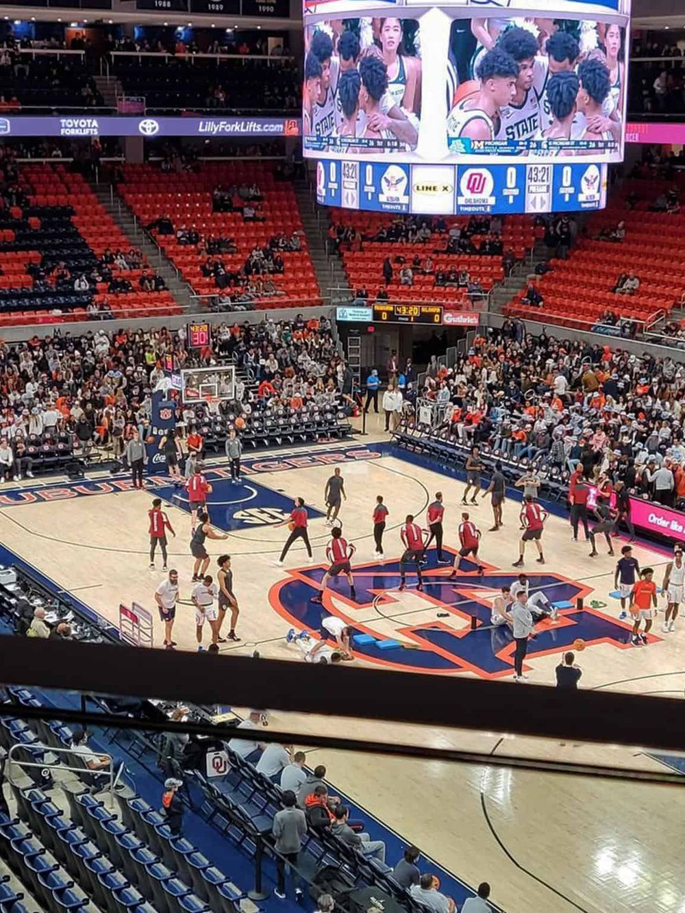 Fast-paced basketball game at an indoor arena with cheering fans and a large digital scoreboard.