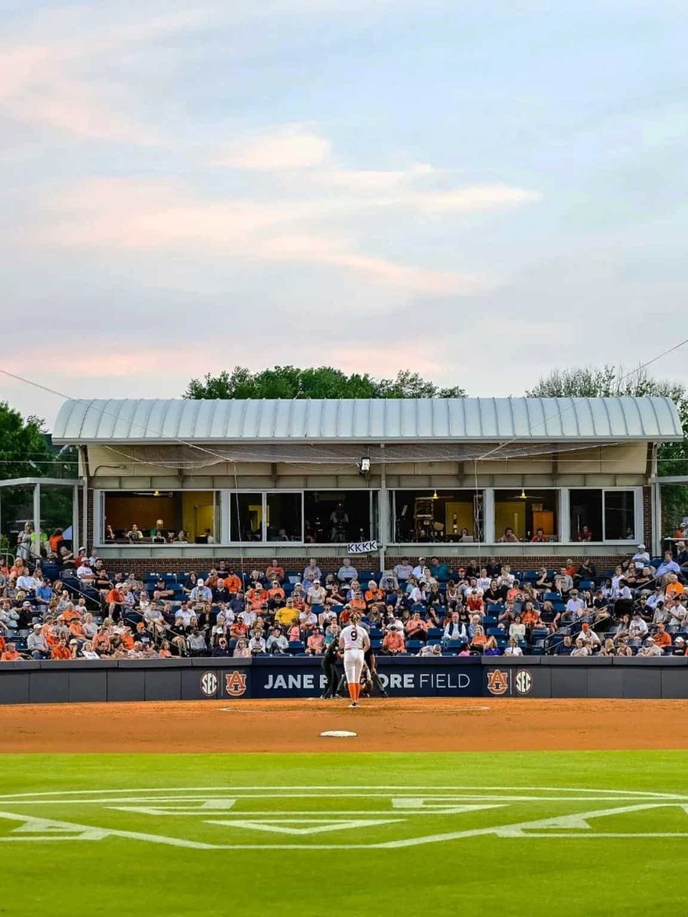 Spectators at a baseball game watching players on the field during an evening game.