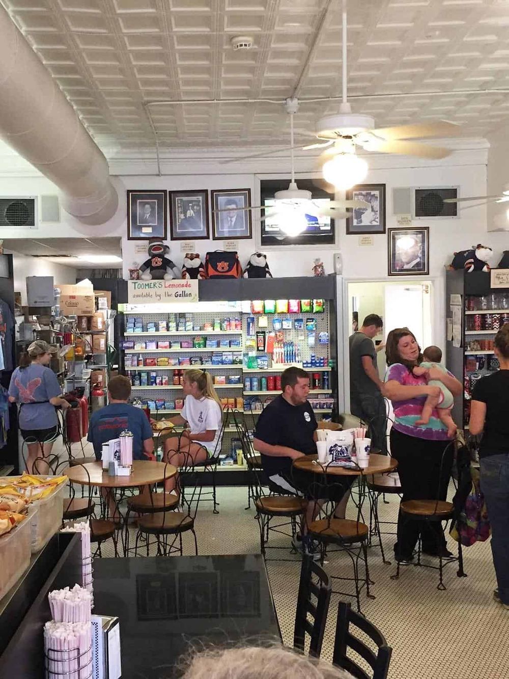 Cozy cafe interior with customers, memorabilia, and a wall display of framed photos, creating a welcoming dining atmosphere.