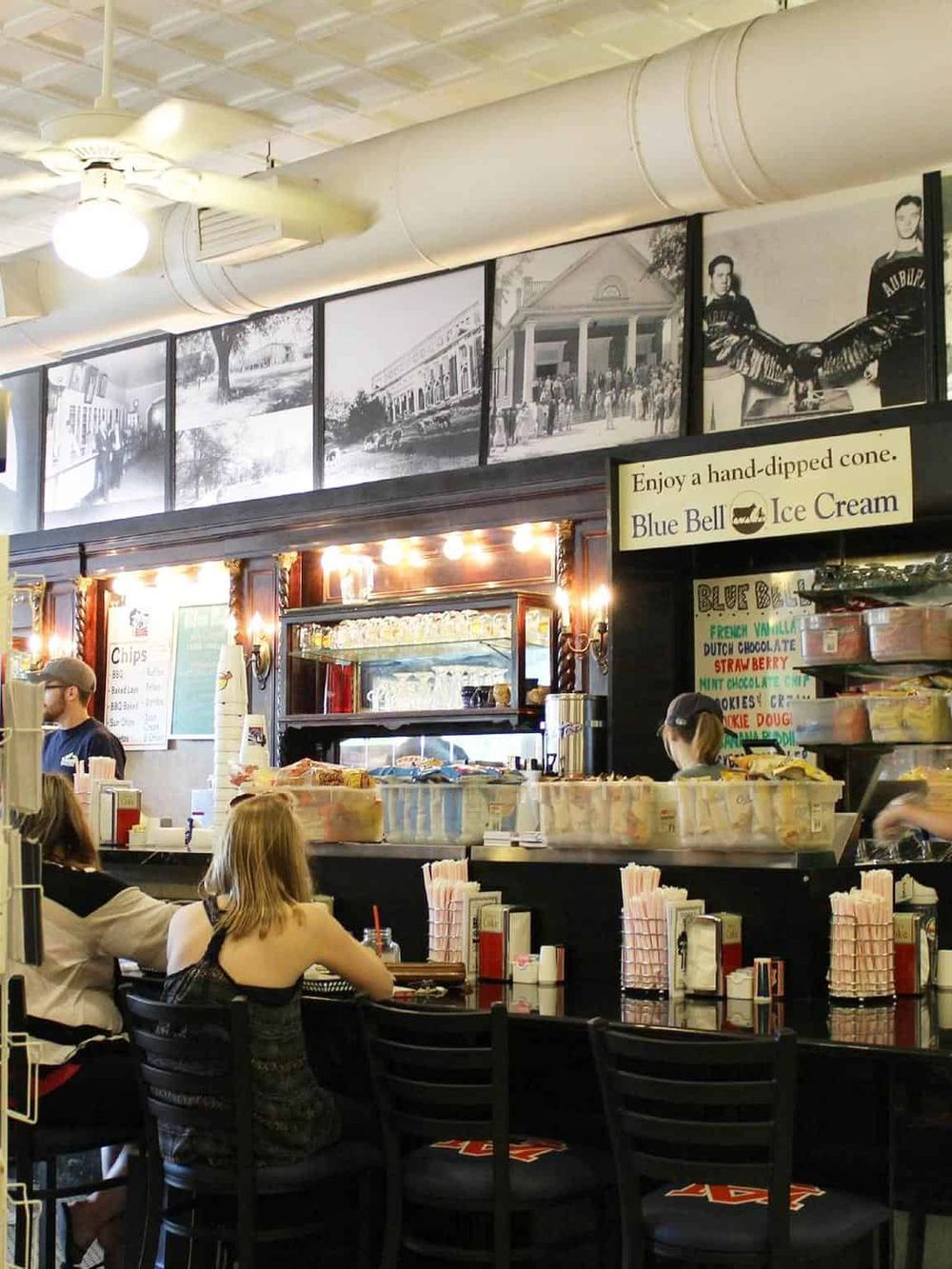 Vintage ice cream shop interior with customers enjoying treats, nostalgic photos, and classic decor.
