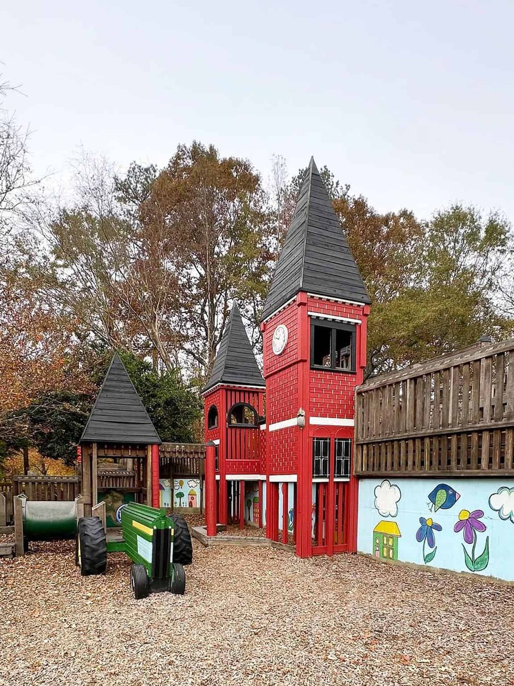 Colorful children's playground with castle towers and a tractor, perfect for family fun and outdoor activities.