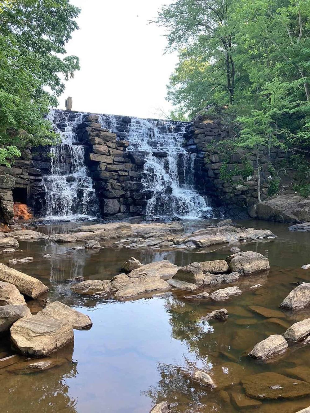 Hidden waterfall with rocks and lush greenery in scenic outdoor setting.
