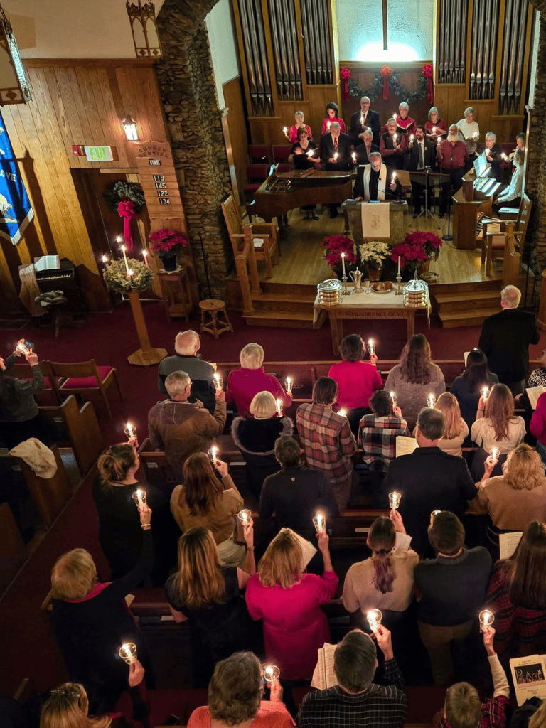 Silent Christmas candlelight service at a church with choir, decorated with poinsettias and candles during the holiday season.