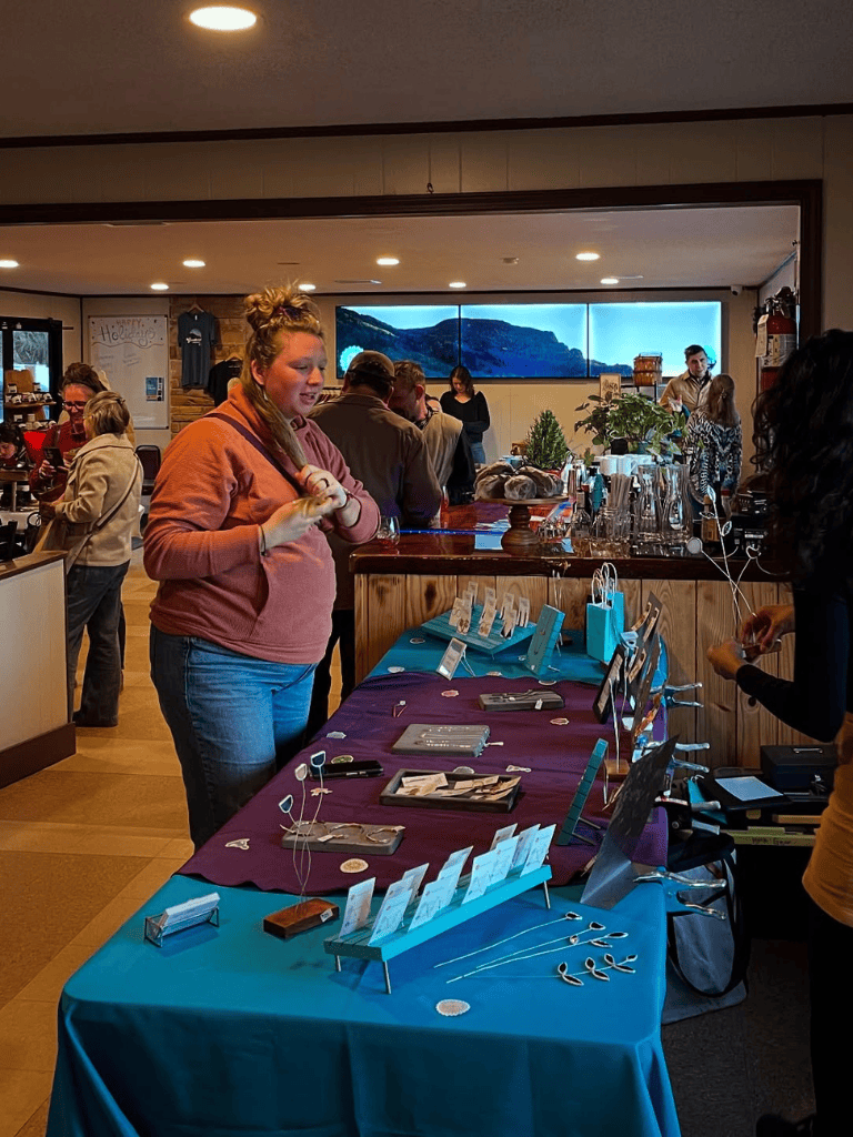 Colorful indoor event with people shopping jewelry at QuestForDirections, a local artisan market.