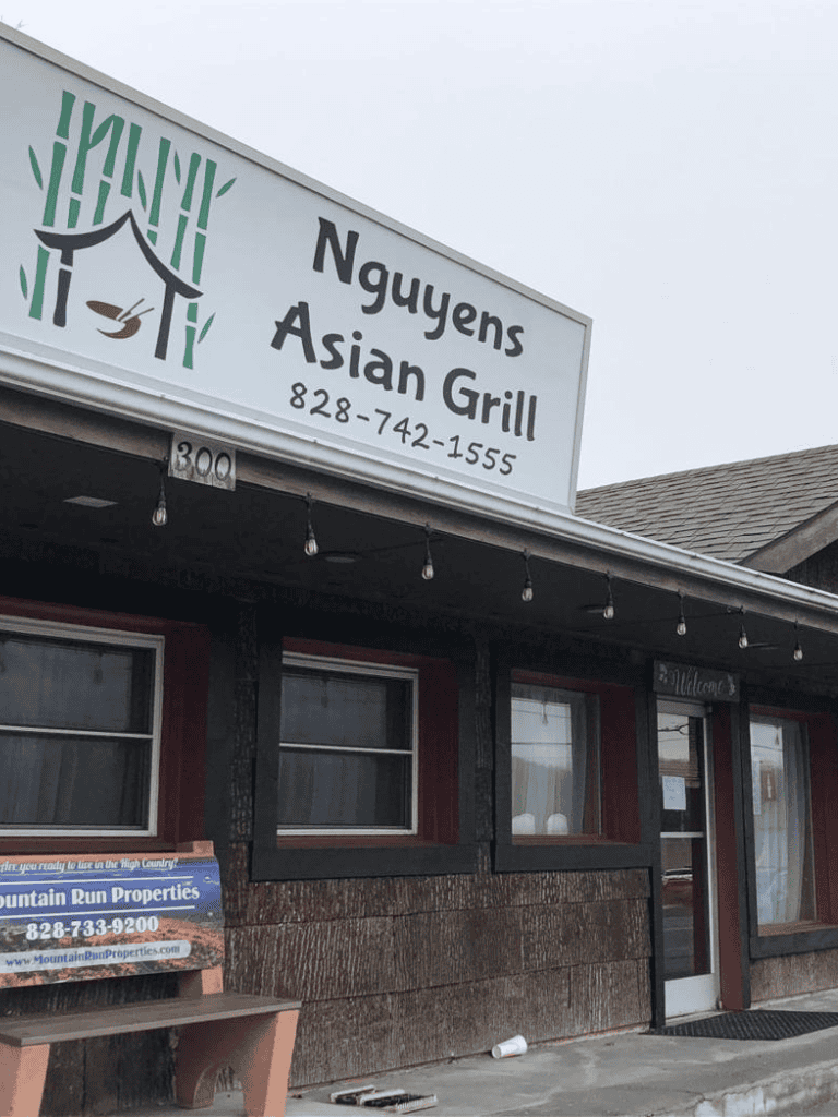 Asian grill restaurant signboard with contact information and welcoming ambiance.