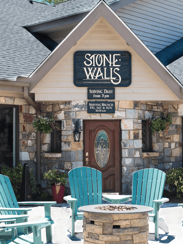 Stone walls restaurant exterior with outdoor seating and serving brunch sign.
