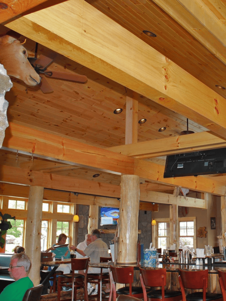 Cozy rustic restaurant interior with wooden beams, stone accents, and warm lighting for a welcoming dining experience.