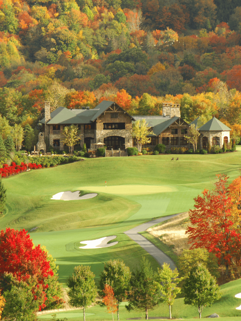 Vibrant autumn landscape featuring a luxurious golf course and a elegant clubhouse amidst colorful fall foliage.
