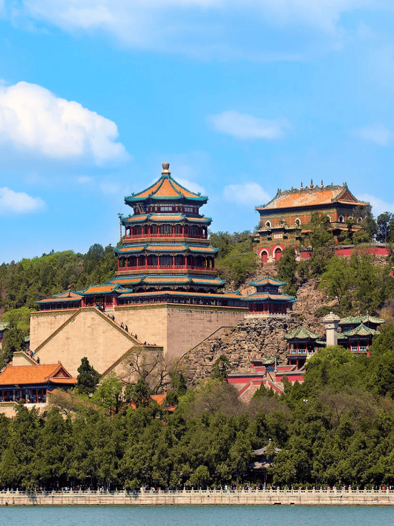 Ornate Chinese temple on a hillside with lush greenery and blue sky, scenic traditional architecture.