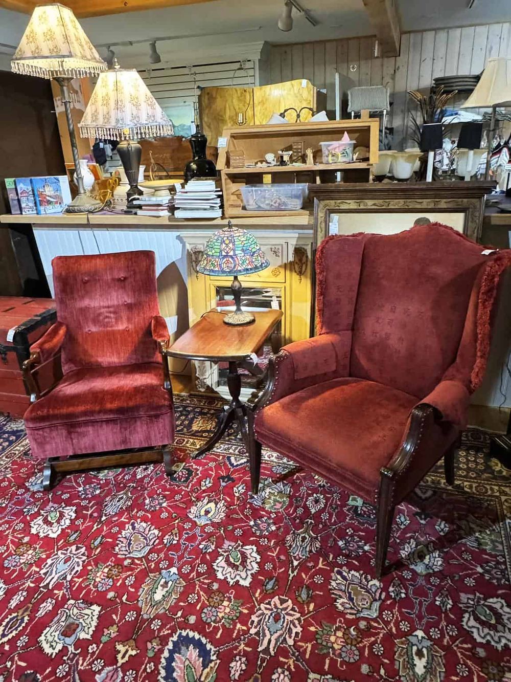 Vintage armchairs and table in an antique store with assorted décor items.