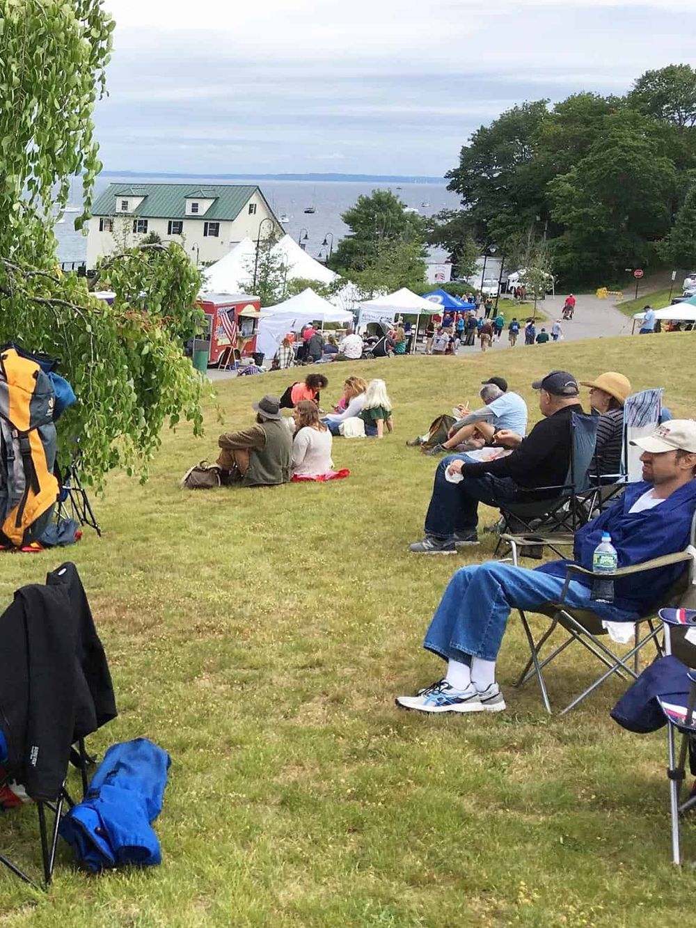 Vibrant outdoor event at QuestForDirections with attendees enjoying scenic waterfront views and lively local market atmosphere.