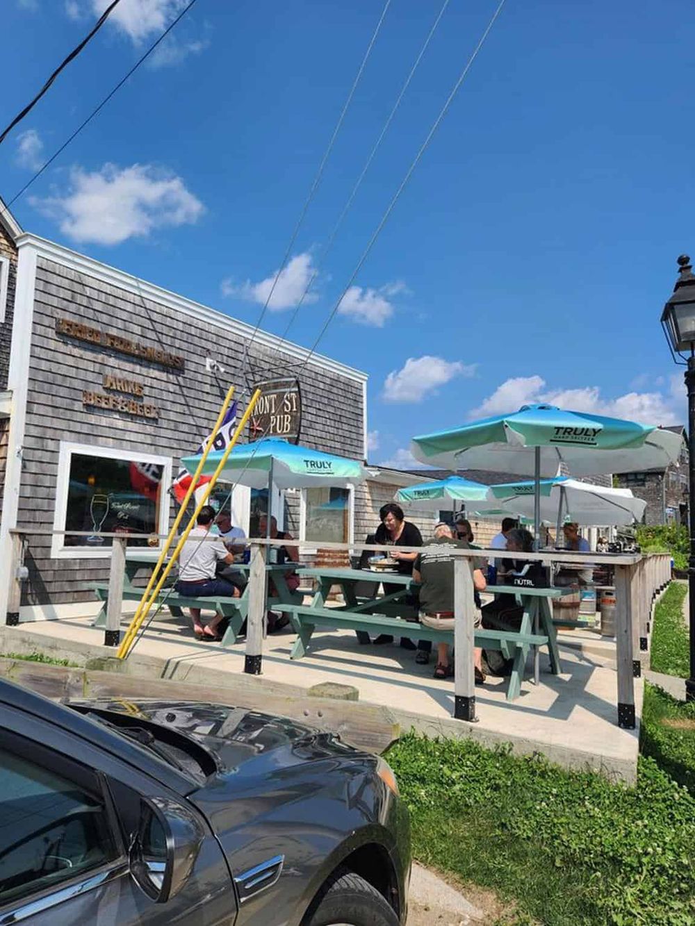 Outdoor dining at a popular pub on a sunny day with umbrellas, in a lively neighborhood.